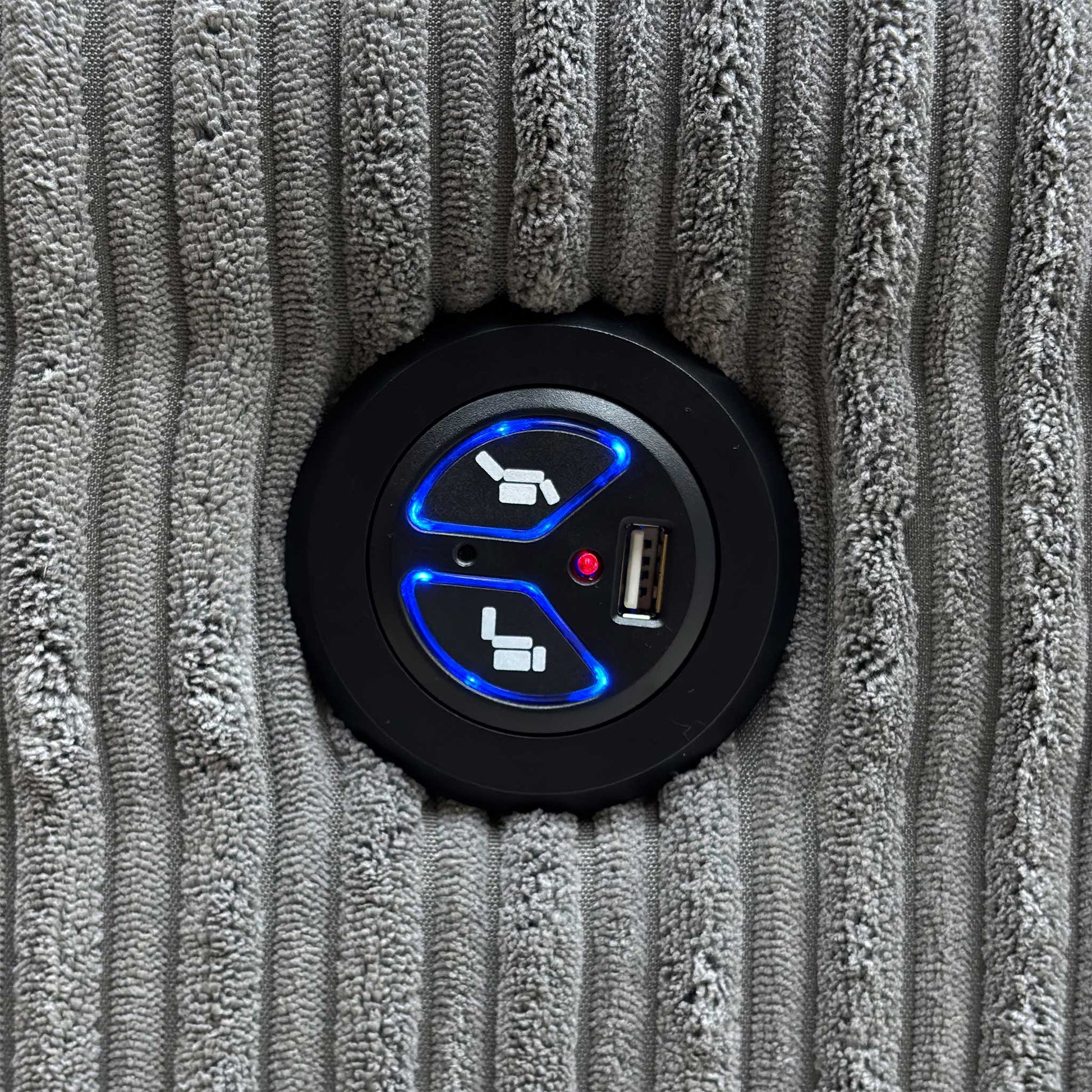 Close-up view of the side-mounted power controls, showing the metallic button mechanism used to adjust the recliner and integrated power functions.