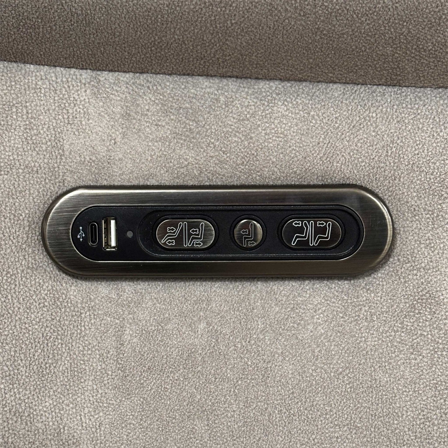 Detail shot of the integrated side control panel, showing the metallic buttons for power recline and headrest adjustment alongside a built-in USB charging port.