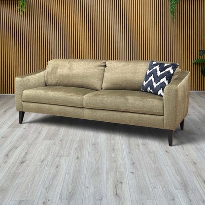Lifestyle view of the Oslo sofa in Vogue Olive, showcasing the deep seat cushions and the elegant contrast between the green velvet and the slim dark legs.