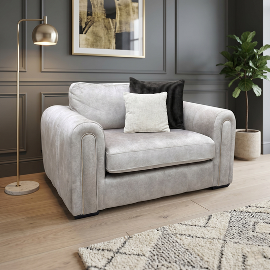 Living room view for the Amara snuggle chair, highlighting its spacious 1.5-seater design, high-density comfort foam cores, and elegant stone fabric upholstery.