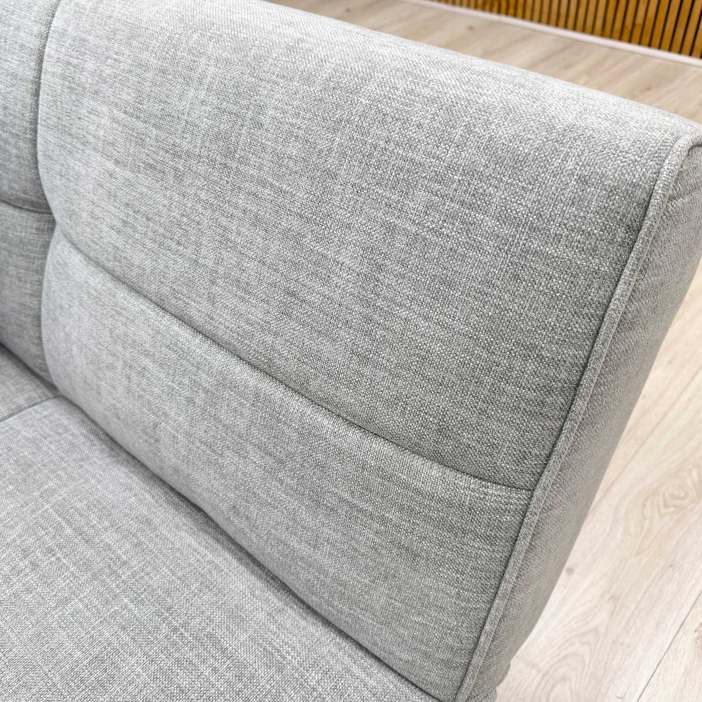 Close-up shot of the Mist Grey fabric upholstery on the ‘Miyagi’ sofa bed, showcasing the deep button detailing and the resilient, multi-tonal grey woven texture.