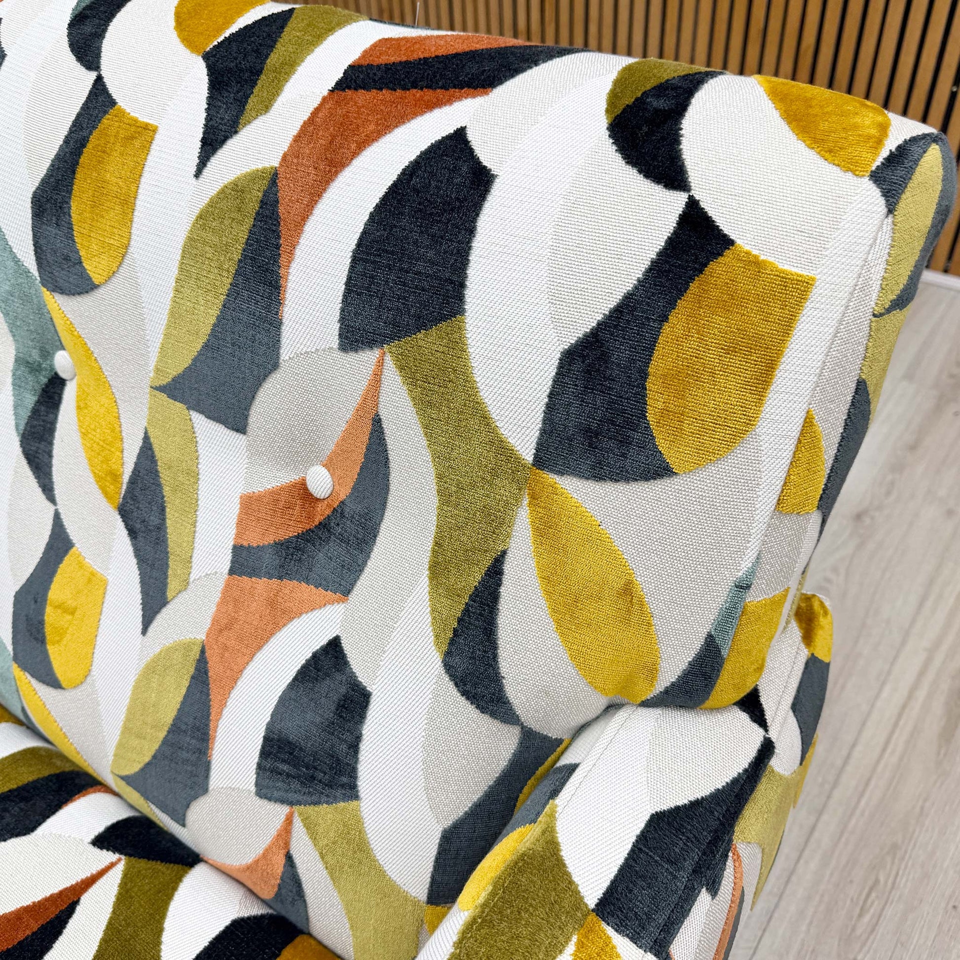 Close-up shot of the Audley Terrazzo patterned velvet upholstery on the ‘Hedingham’ chair, showcasing the intricate multi-colored abstract design and plush, tactile texture.