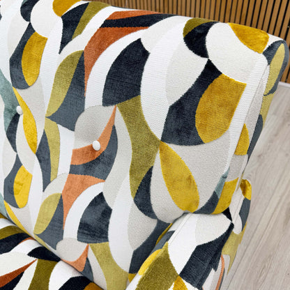 Close-up shot of the Audley Terrazzo patterned velvet upholstery on the ‘Hedingham’ chair, showcasing the intricate multi-colored abstract design and plush, tactile texture.