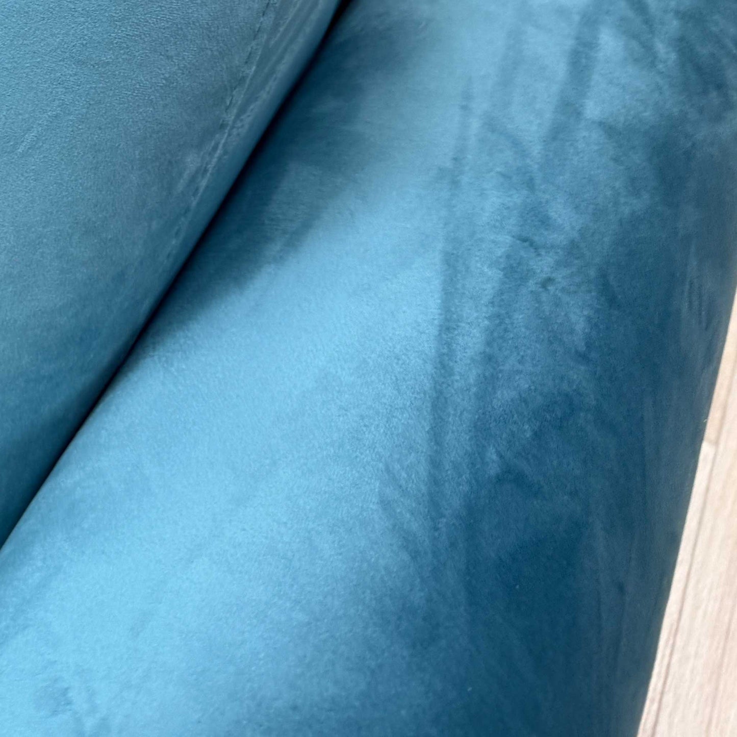 Close-up shot of the luxurious teal velvet fabric on the ‘Alcova’ sofa, showcasing the vibrant jewel tone and the rich, textured finish of the upholstery.