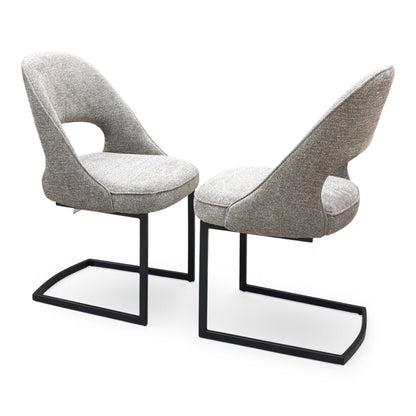 Side profile of the ‘Tiber’ dining chair, highlighting the clean, continuous curve of the matte black powder-coated cantilever base and the ergonomic slant of the backrest.