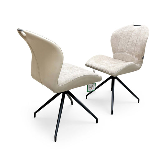 Full view of the Raul set of 2 swivel dining chairs in pebble taupe fabric, showcasing their modern bucket seat design, vertical channel tufting, and black metal tapered legs.