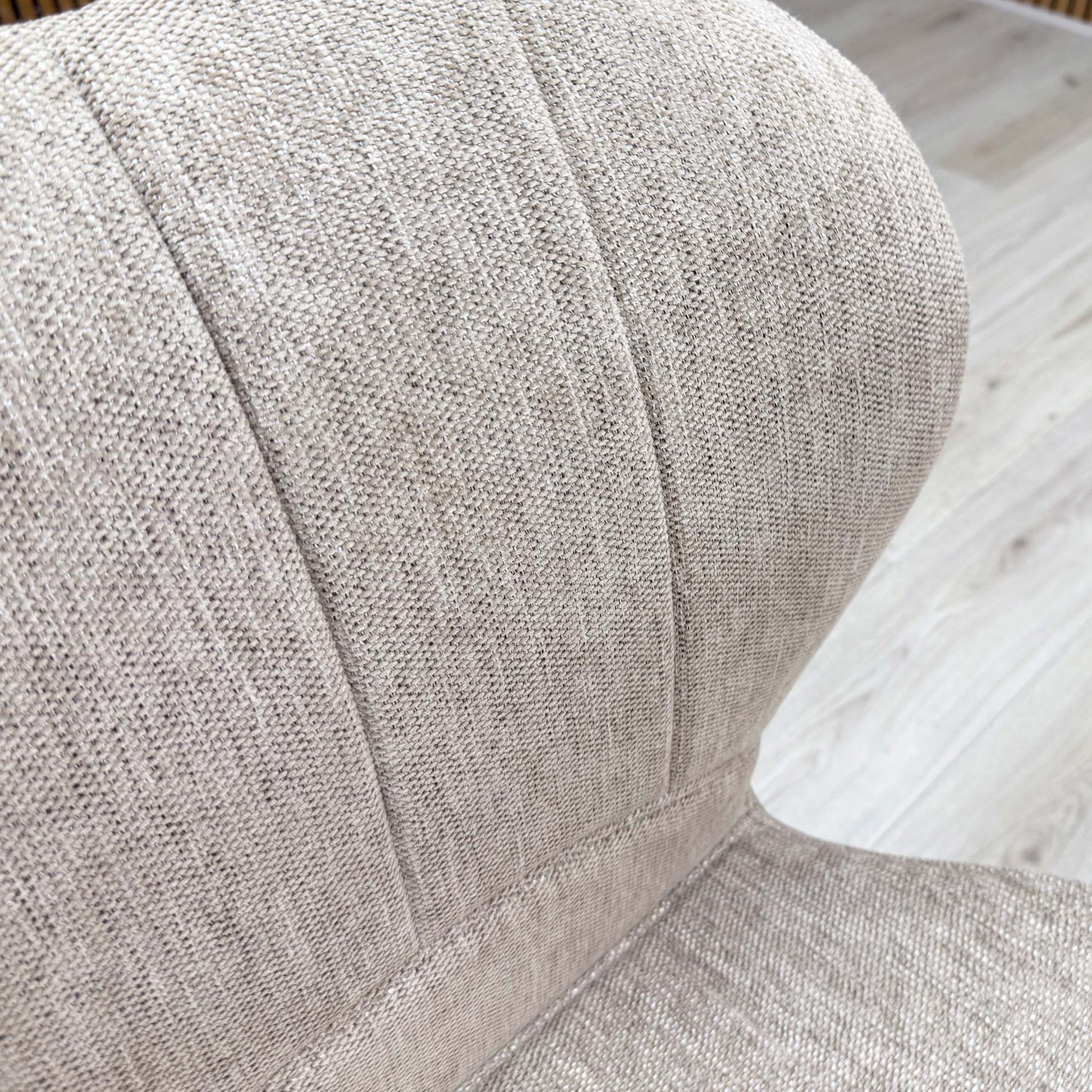 Macro detail of the Raul dining chair upholstery, showing the high-quality texture of the pebble taupe fabric and the precise vertical channel-stitched backrest panel.