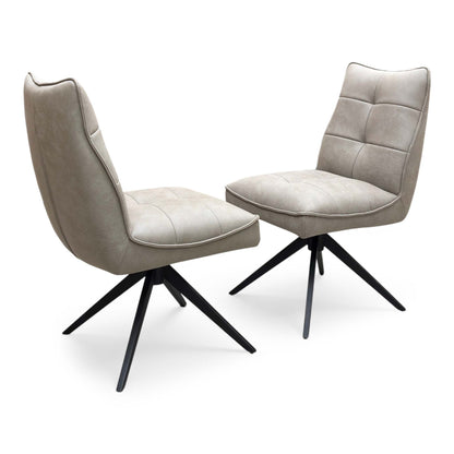 Full view of a pair of ‘Germain’ Swivel Dining Chairs in Taupe faux leather, showcasing their sleek contemporary scoop silhouettes, vertical channel stitching, and elegant black metal legs.