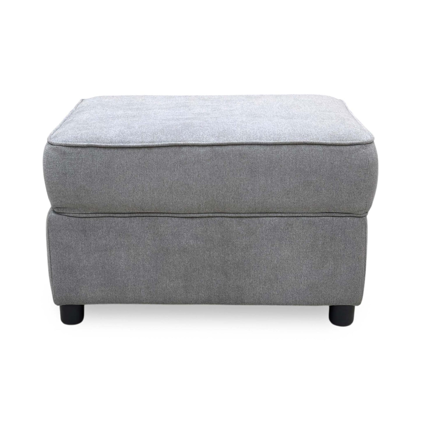 Three-quarter angled view of the Comfi light grey upholstered storage ottoman, highlighting its clean tailored seams, fabric texture, and low-profile feet.