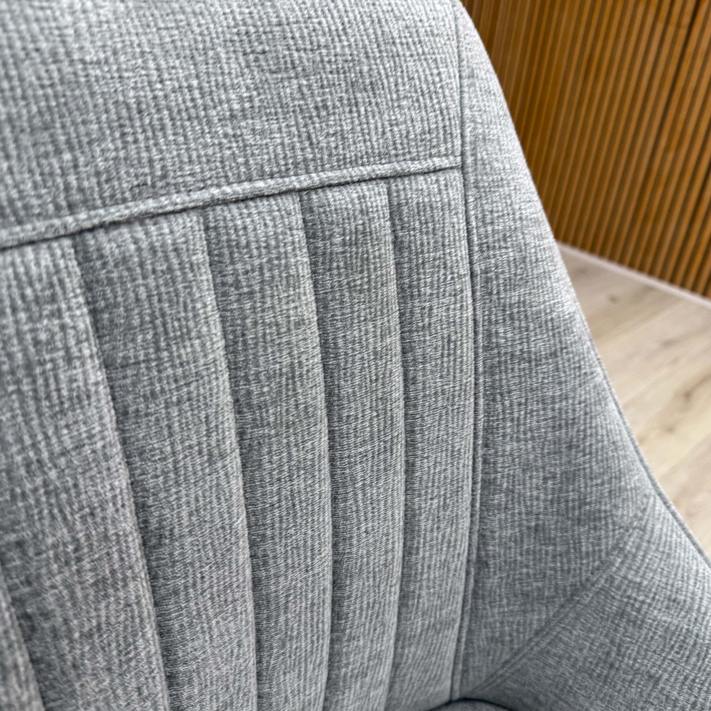 Close-up macro detail of the high-quality silver fabric upholstery, showcasing the fine textured weave pattern and its light-reflective, modern metallic tone.