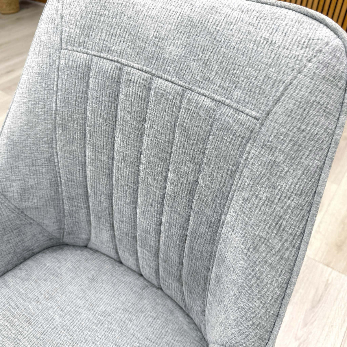 Close-up of the silver textured fabric and vertical stitching on the Crete dining chair back