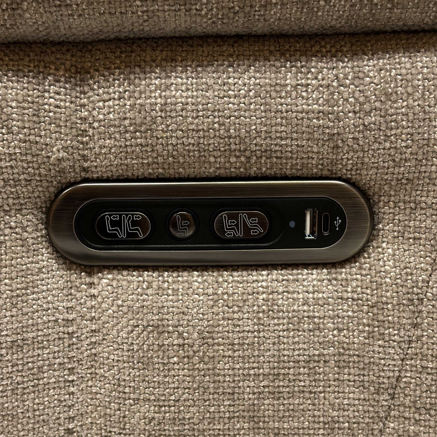 Detailed view of the sleek metallic outer armrest control switch panel, featuring integrated buttons for independent power recline and headrest adjustments.