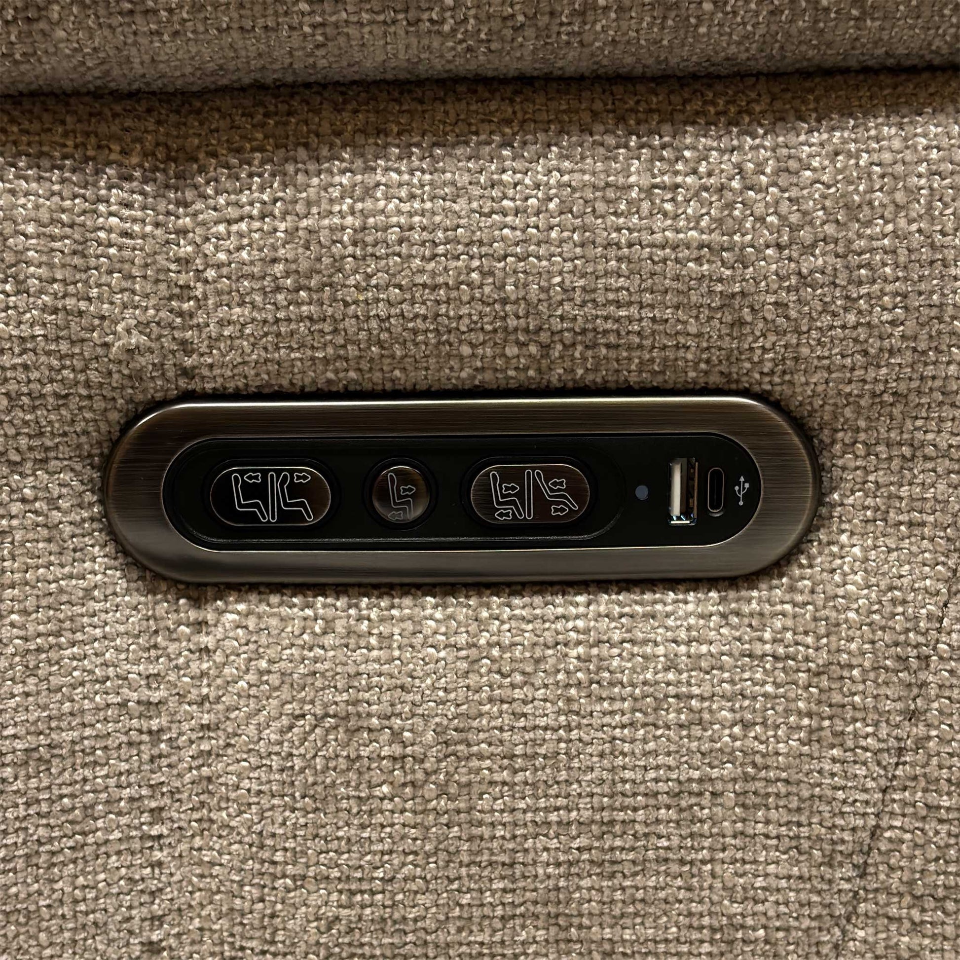 Detailed view of the sleek metallic outer armrest control switch panel, featuring integrated buttons for independent power recline and headrest adjustments.