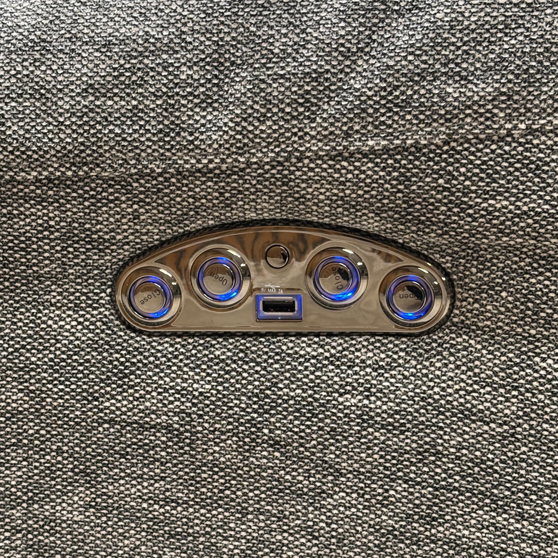 Macro view of the Link SKA-R31 charcoal grey fabric, emphasizing the high-quality woven textile texture, tight seams, and side control panel with an integrated USB charging port.