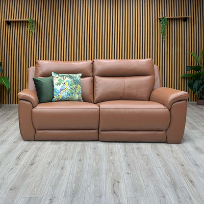 Lifestyle view three-quarter angled view of the Bobby tan leather power reclining couch, highlighting the generous seat depth, robust armrests, and premium tailored contrast stitching.