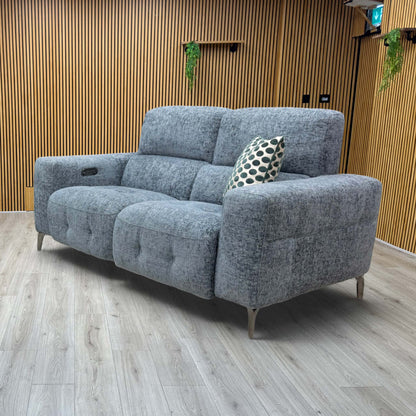 Lifestyle view of  three-quarter angled view of the New York silverish blue power reclining fabric couch, highlighting its contemporary tailored design and vibrant mid-tone finish.