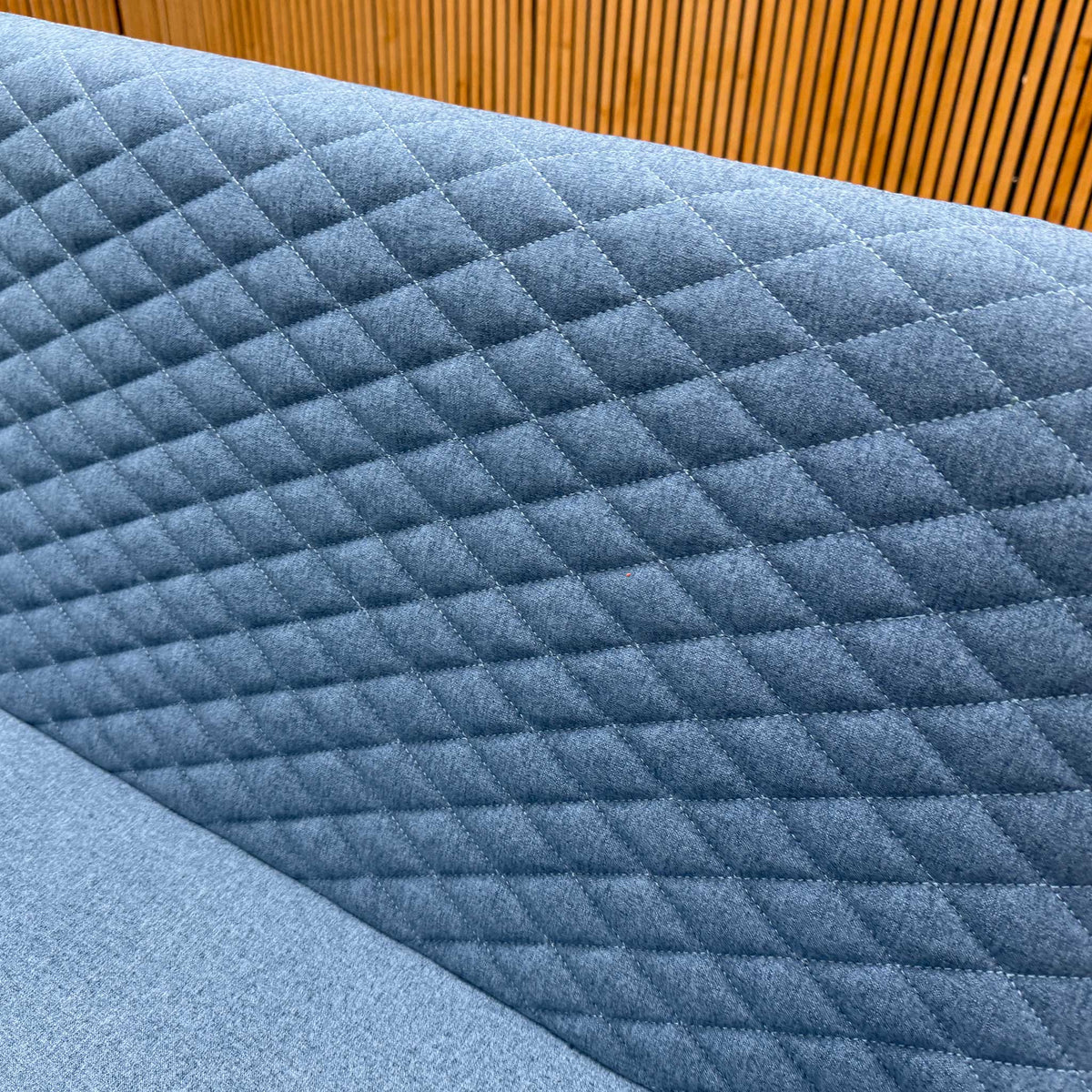 Close-up of the diamond quilting on the mineral blue fabric back of the Rocket dining bench