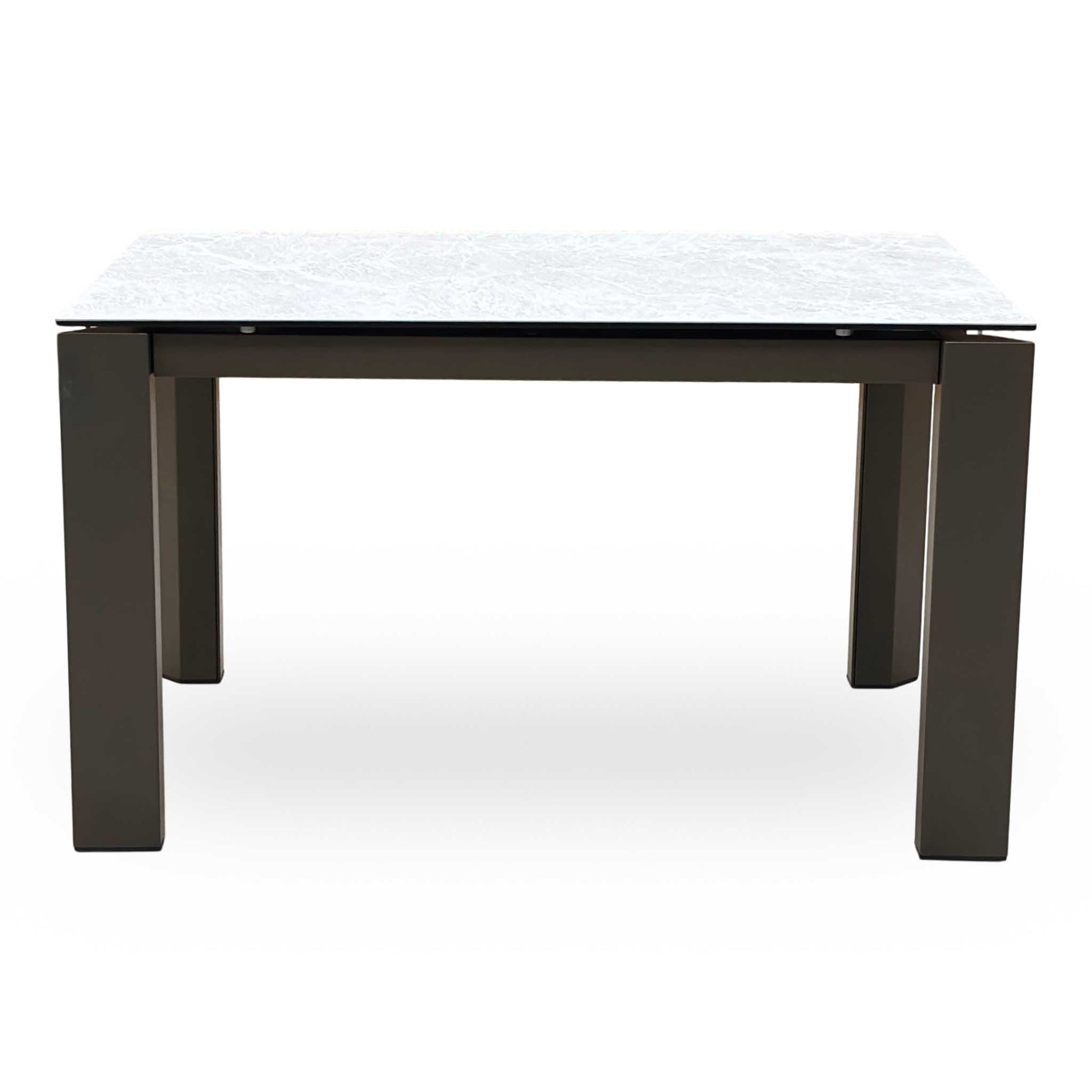 Front-facing view of the Connubia Viola dining table in its standard unextended position, highlighting the seamless clean lines, elegant corner-positioned legs, and architectural silhouette.