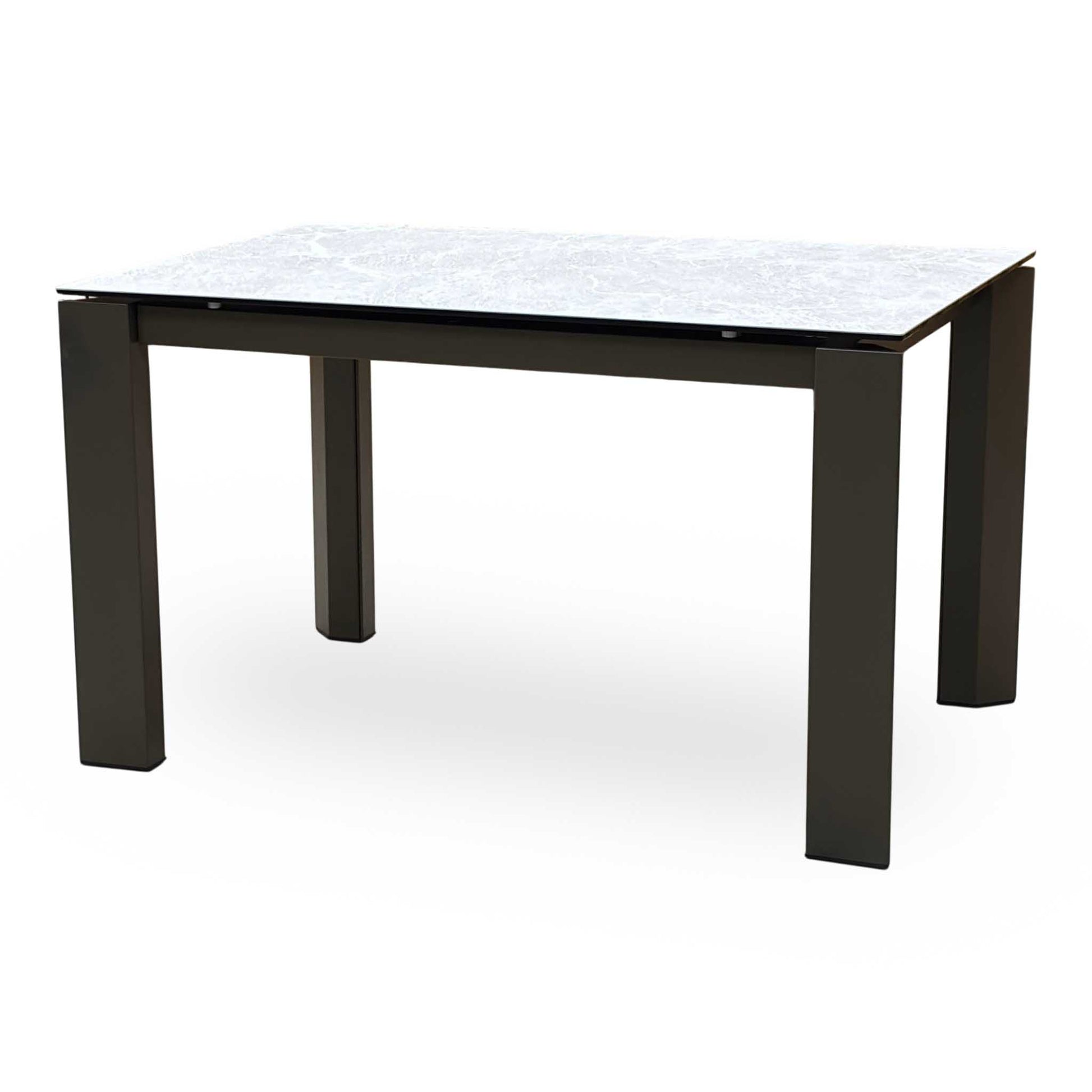 Side view of the dining table fully extended, highlighting the additional matching ceramic leaf locked in place while the legs remain at the corners to maximize guest legroom.