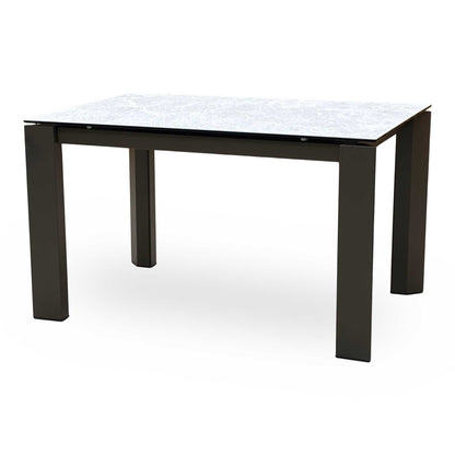 Side view of the dining table fully extended, highlighting the additional matching ceramic leaf locked in place while the legs remain at the corners to maximize guest legroom.