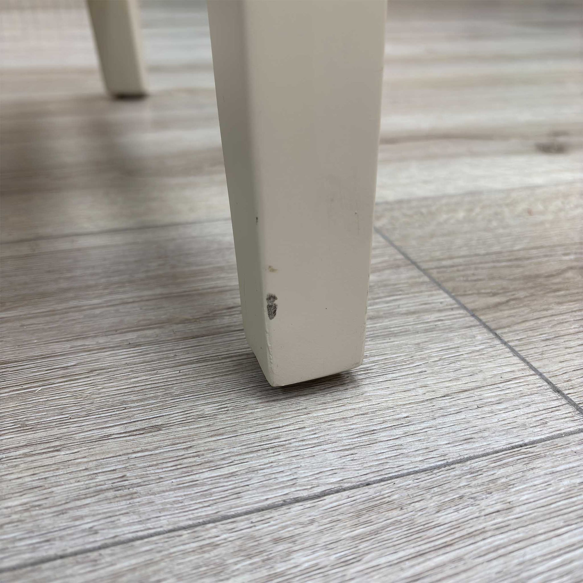 Close-up view from a high angle looking down at the seat and backrest junction, displaying the flawless edge finishing, tight tolerances, and pristine tailored construction lines.Damage on chair leg.