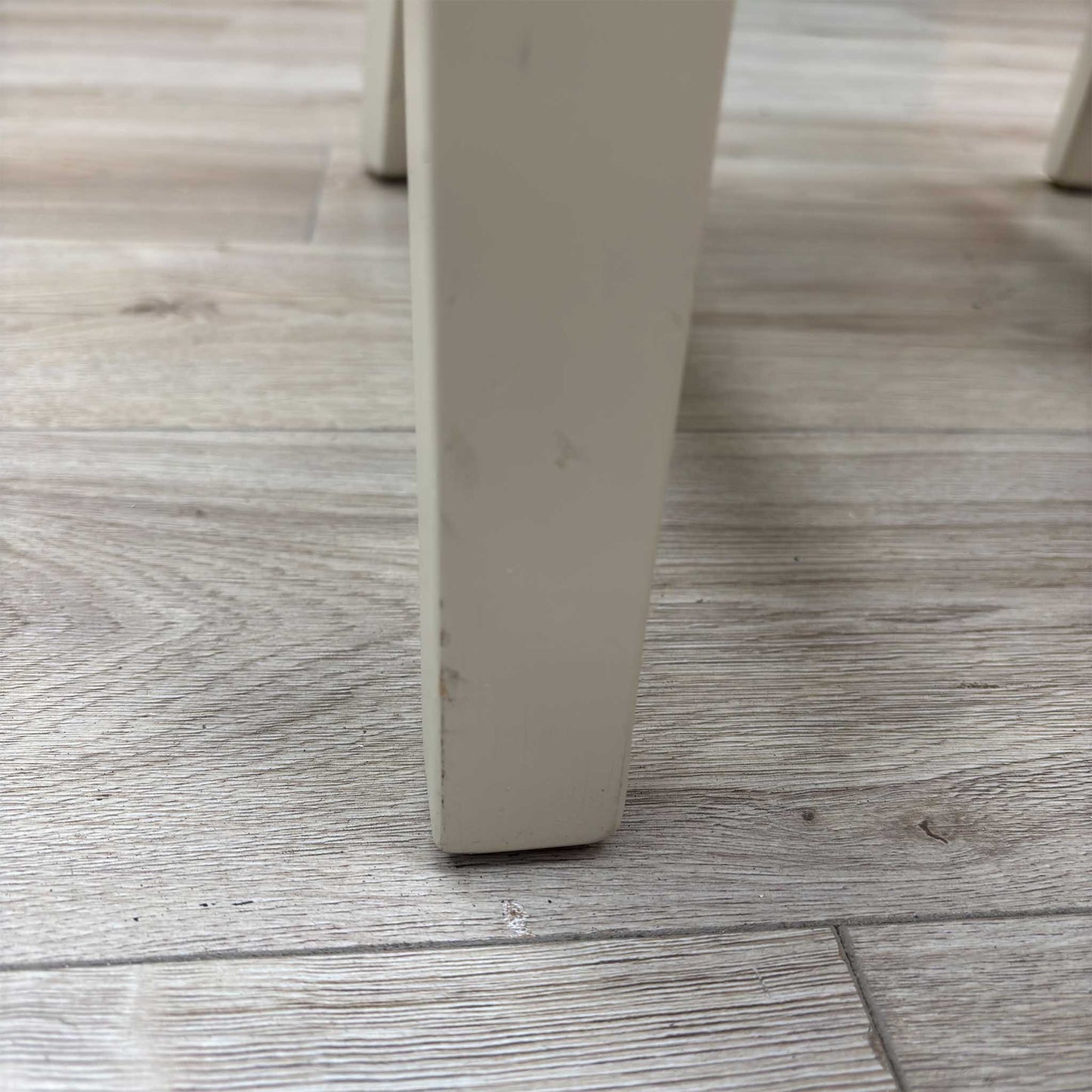 Close-up view from a high angle looking down at the seat and backrest junction, displaying the flawless edge finishing, tight tolerances, and pristine tailored construction lines.Damage on chair leg.