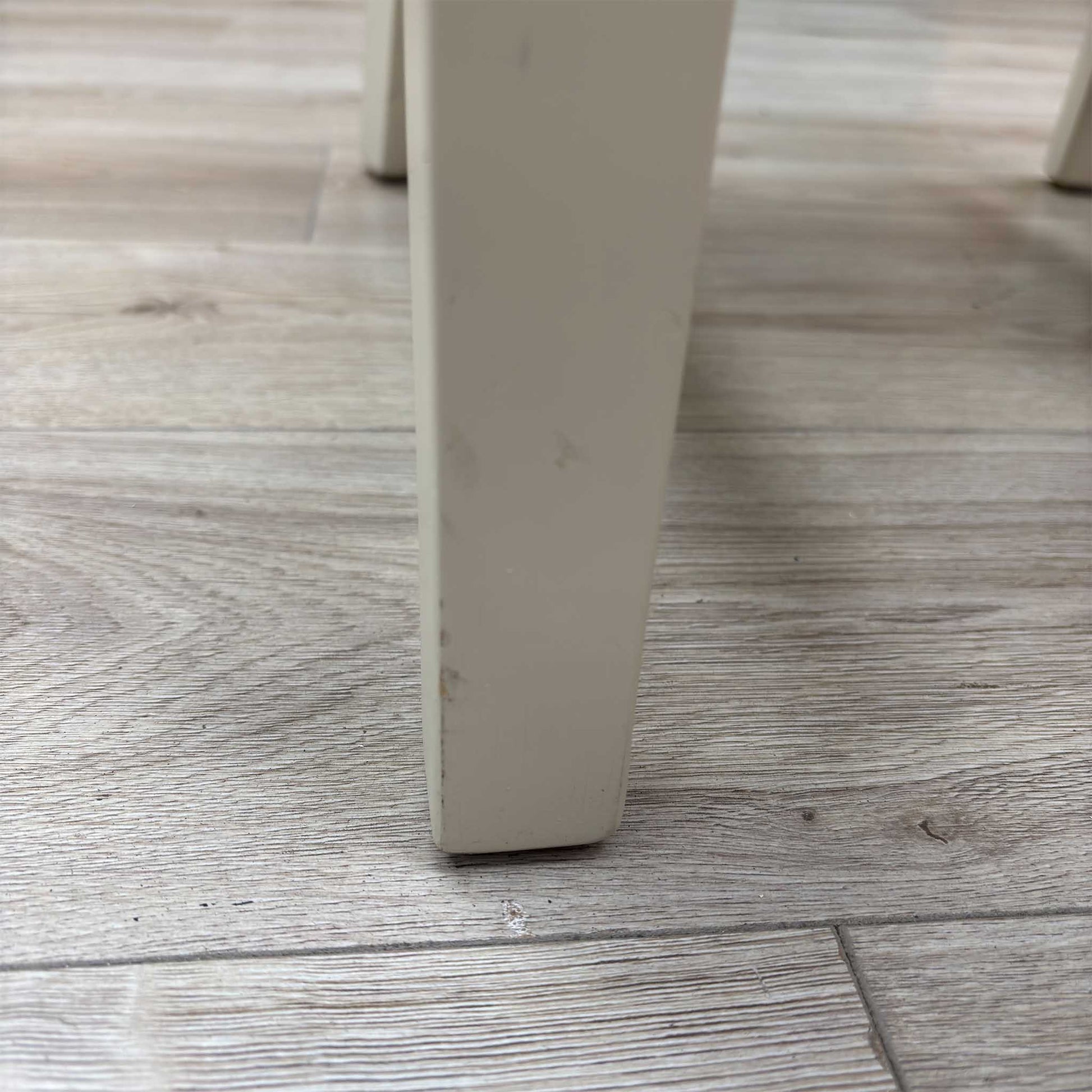 Close-up view from a high angle looking down at the seat and backrest junction, displaying the flawless edge finishing, tight tolerances, and pristine tailored construction lines.Damage on chair leg.