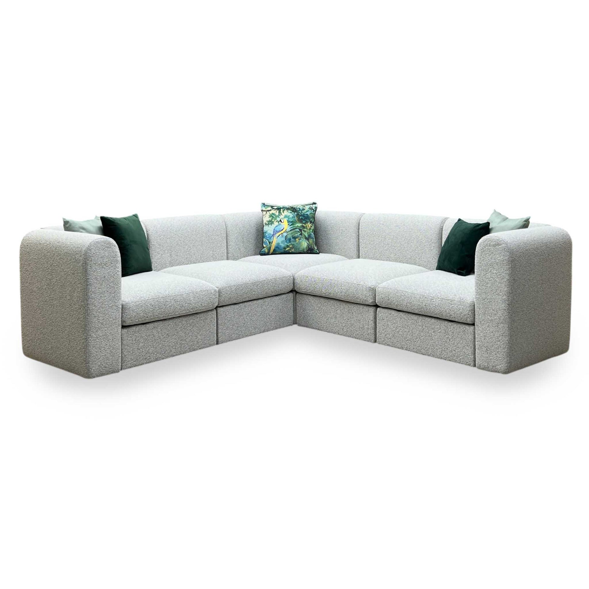 Gray sectional sofa with green and patterned cushions on a white background