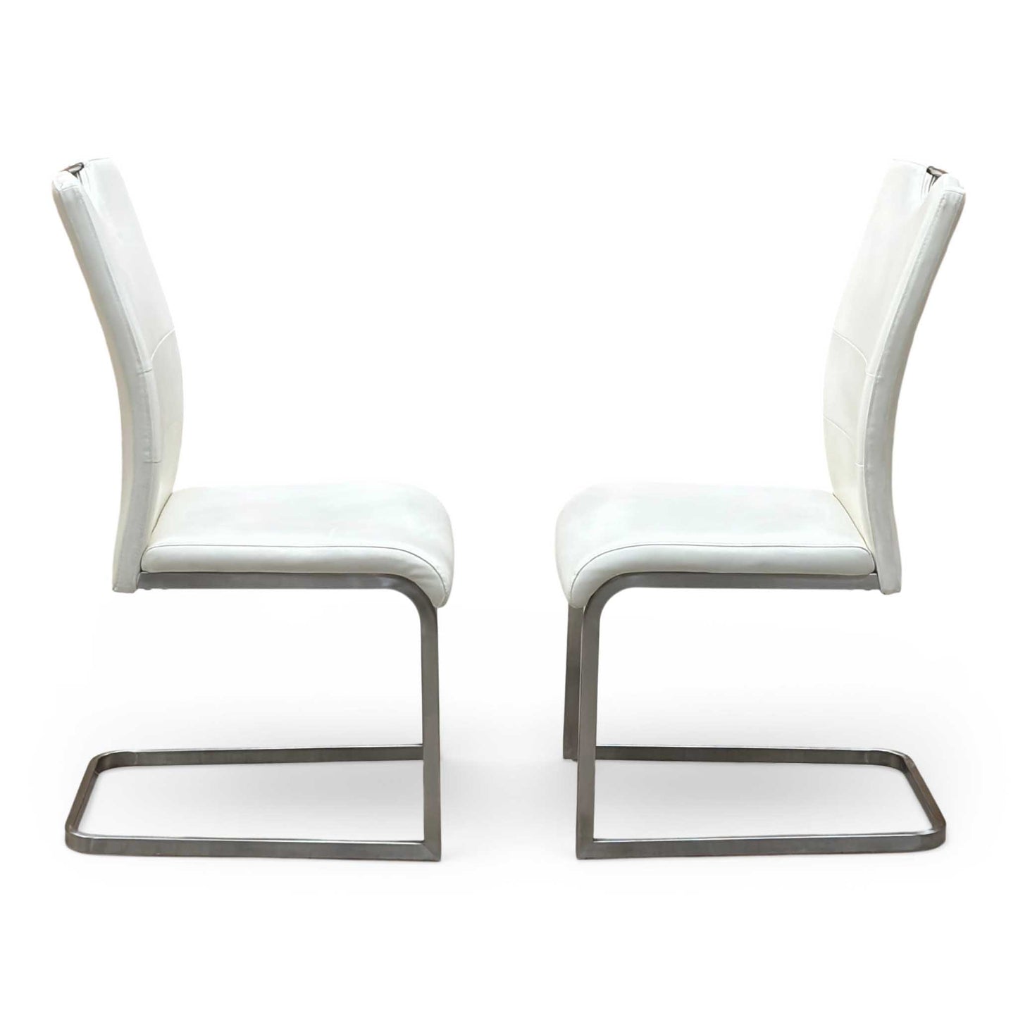 Front-facing view of the two Bianco white faux leather dining chairs arranged side-by-side, highlighting their clean vertical stitching patterns, contoured padded seats, and elegant symmetry.