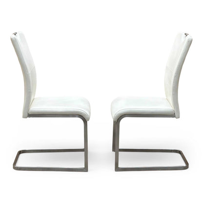 Front-facing view of the two Bianco white faux leather dining chairs arranged side-by-side, highlighting their clean vertical stitching patterns, contoured padded seats, and elegant symmetry.
