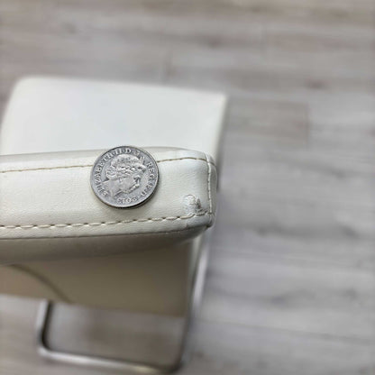 Small defect on the chair.High-definition close-up macro view of the Bianco White faux leather upholstery, detailing the premium fine-grain surface texture, pristine matte finish, and clean modern tailoring lines.