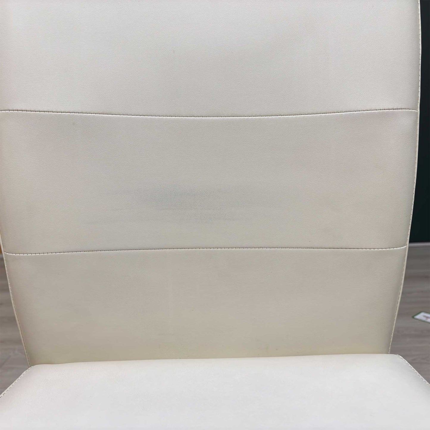 Close-up view from a high angle looking down at the seat cushion, displaying the flawless fabric tensioning across the padded surface, tight corner seams, and precise perimeter stitching.Small defect on the chair.