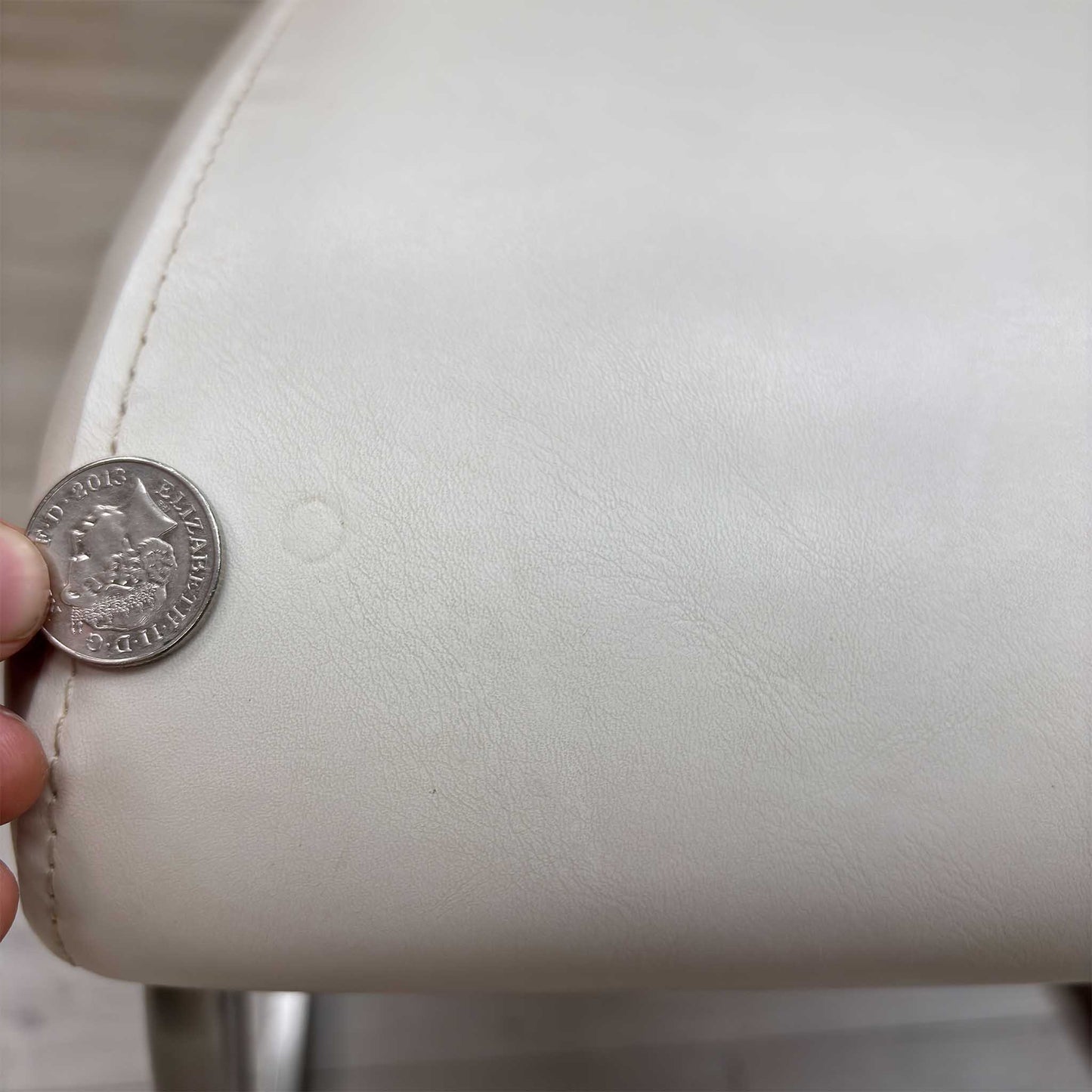 High-definition close-up macro view of the Bianco White faux leather upholstery, detailing the premium fine-grain surface texture, pristine matte finish, and clean modern tailoring lines.Small defect on the chair.