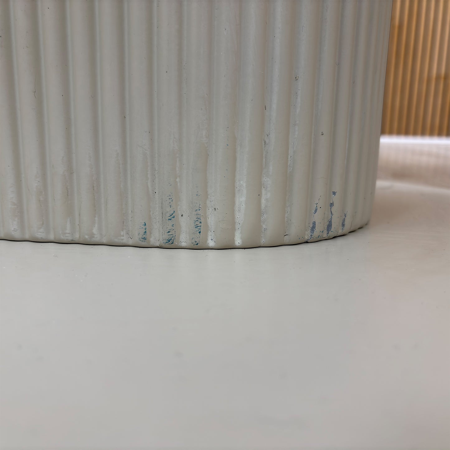 Detailed view of the modern architectural pedestal base on the Avorio ceramic dining table. Highlights the heavy-duty fluted or ribbed column support frame and the sleek matching floor-anchoring base plate.