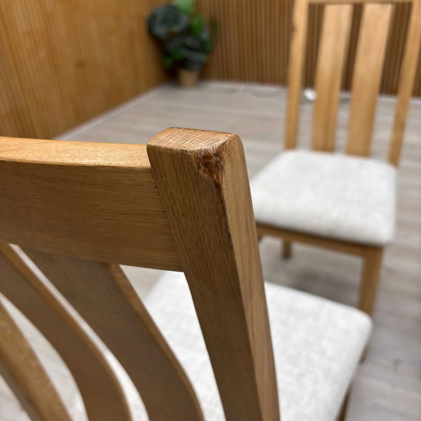 close-up macro view focusing on the backrest woodwork, highlighting the smooth finish, rich natural grain patterns of the timber, and the precise alignment of the vertical slats.Small defect on the chair.