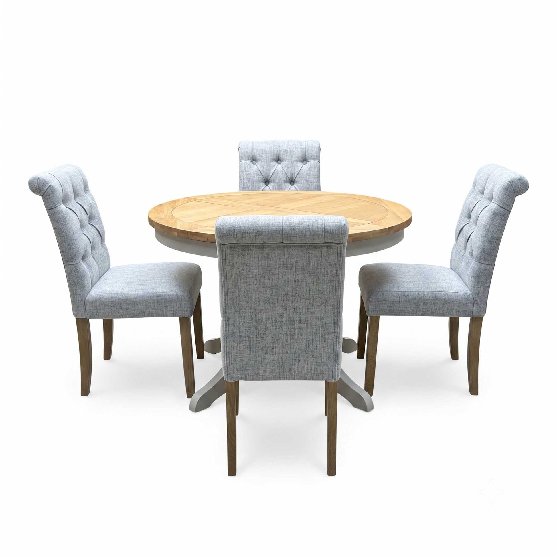 ‘Lewis’ Natural Oak Round Pedestal Butterfly Extending Dining Table with Mist Grey Fabric Button Back Dining Chairs - Set of 4 Furniture Village