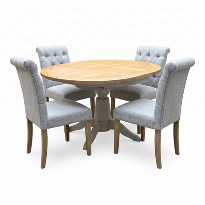 ‘Lewis’ Natural Oak Round Pedestal Butterfly Extending Dining Table with Mist Grey Fabric Button Back Dining Chairs - Set of 4 Furniture Village