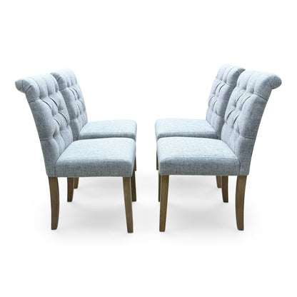 ‘Lewis’ Natural Oak Round Pedestal Butterfly Extending Dining Table with Mist Grey Fabric Button Back Dining Chairs - Set of 4 Furniture Village