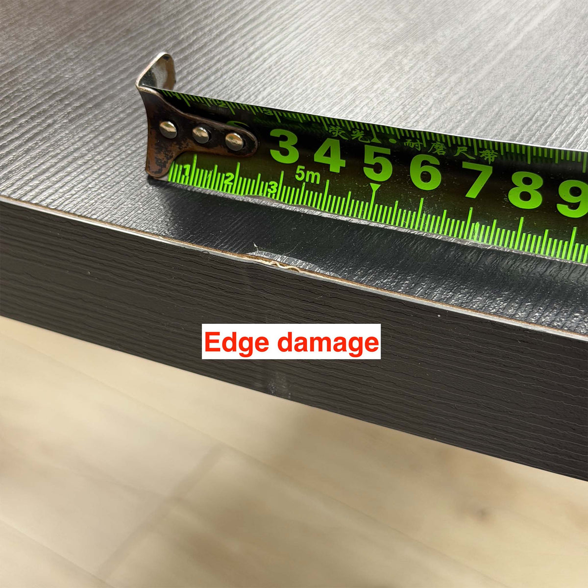 Close-up of edge damage on the Magda black oak table top, measured with a tape measure