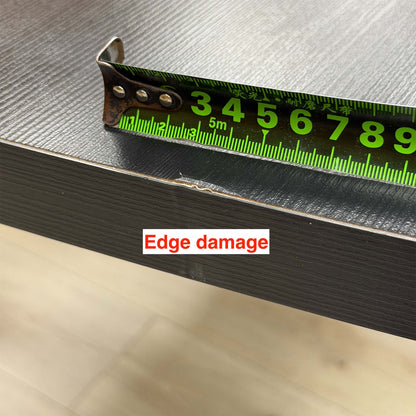 Close-up of edge damage on the Magda black oak table top, measured with a tape measure