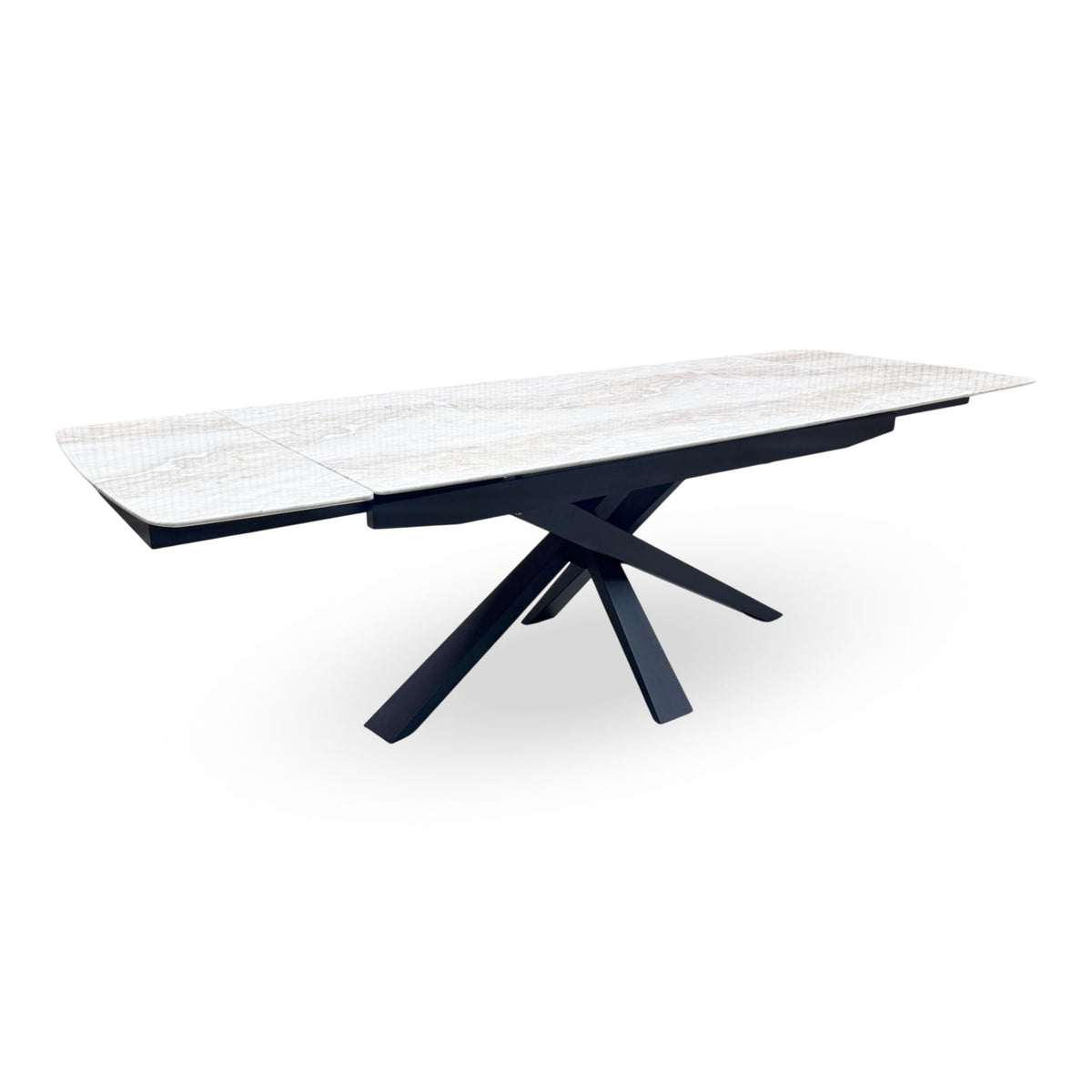 Germain real marble top large extending dining table fully extended on a black metal star base, angled view