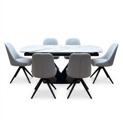 Jose dining set seen from the chair backs, six stone grey swivel chairs around the white marble effect table