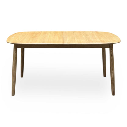 Front view of the Stockholm light oak extending dining table, closed, with darker tapered oak legs