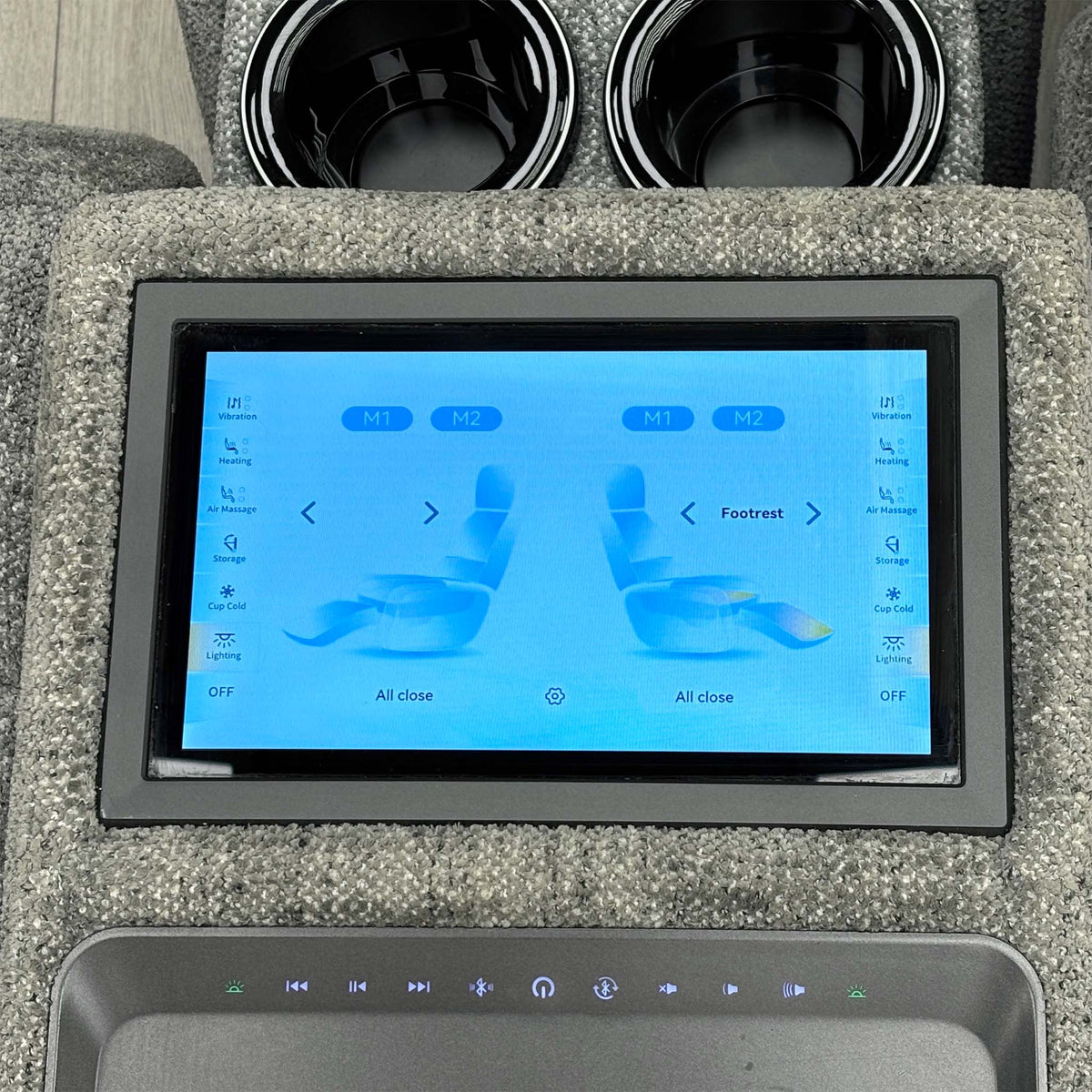 Close-up of the Hollywood media sofa console touchscreen showing recliner and footrest controls, cup holders above