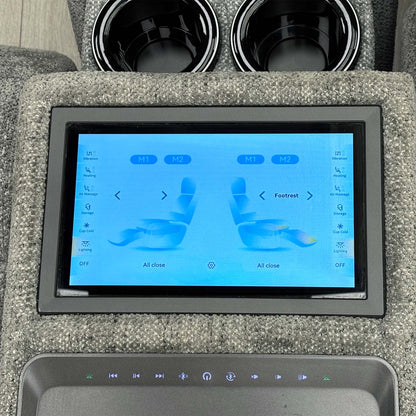 Close-up of the Hollywood media sofa console touchscreen showing recliner and footrest controls, cup holders above