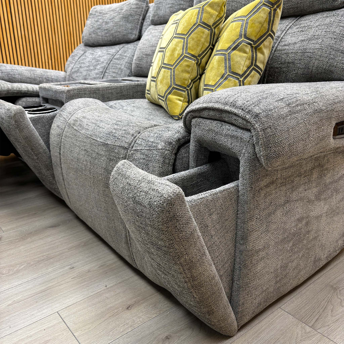 Low angle of the Hollywood dove grey fabric sofa with the right seat reclined, showing the padded arm and side buttons