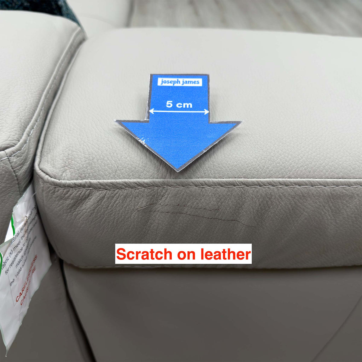 Close-up of the scratch on the leather seat cushion edge of the Brady sofa, marked with a 5cm arrow