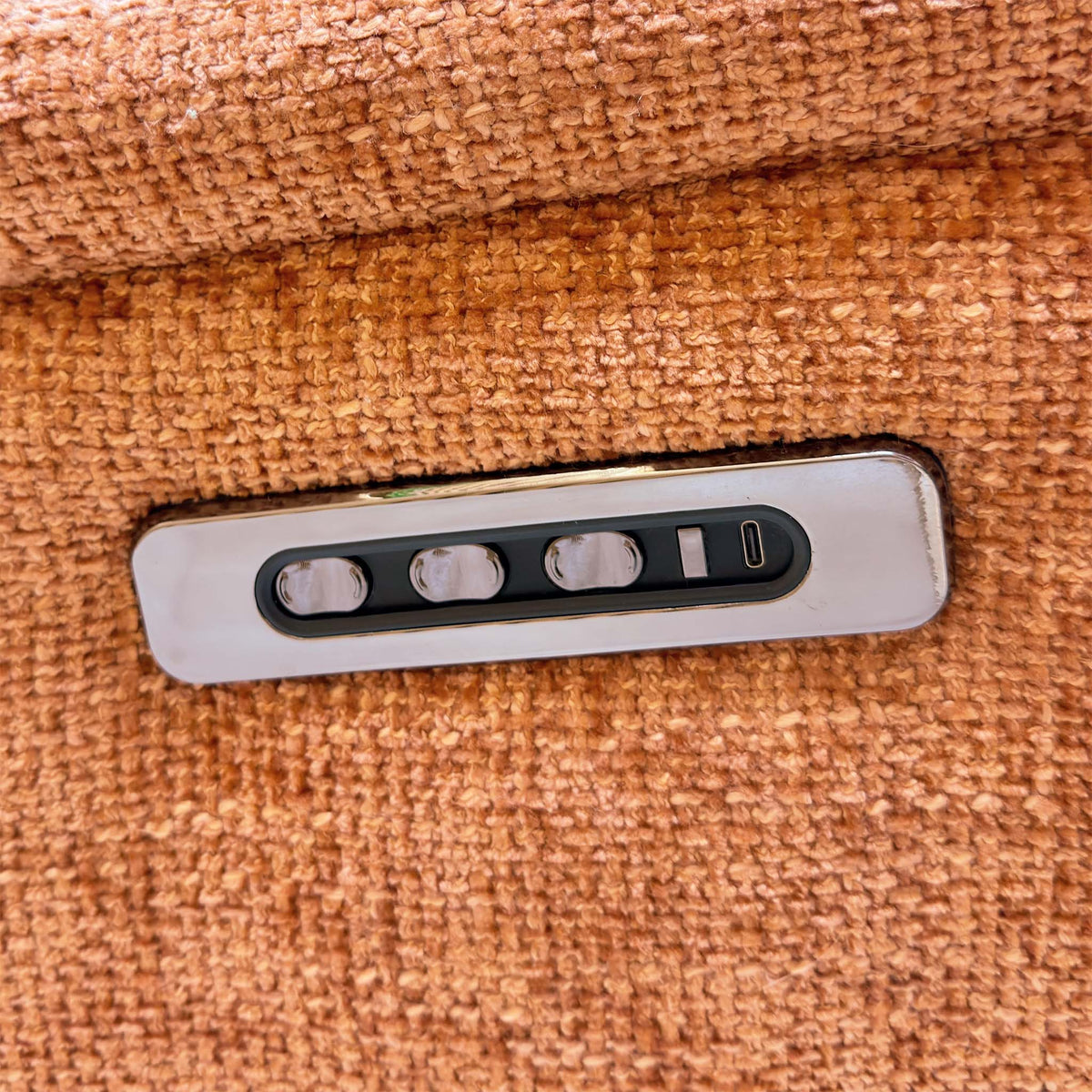 Close-up of the power recline, headrest and lumbar buttons with USB-C port on the Nicoletti Vito orange sofa