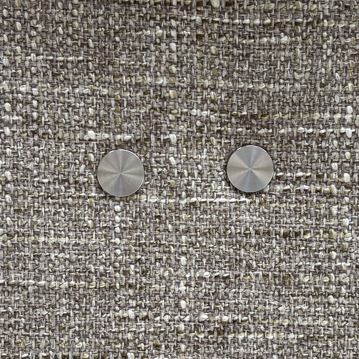 Close-up of the two round metal power recline buttons on the G Plan Malvern oatmeal fabric chair
