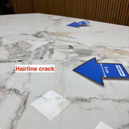 Close-up of a second hairline crack on the Avorio ceramic table top near the grey veining, blue 5cm arrow